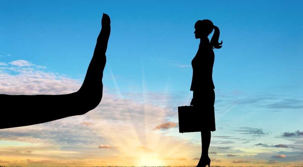 a large hand stopping a young woman, showing discrimination 